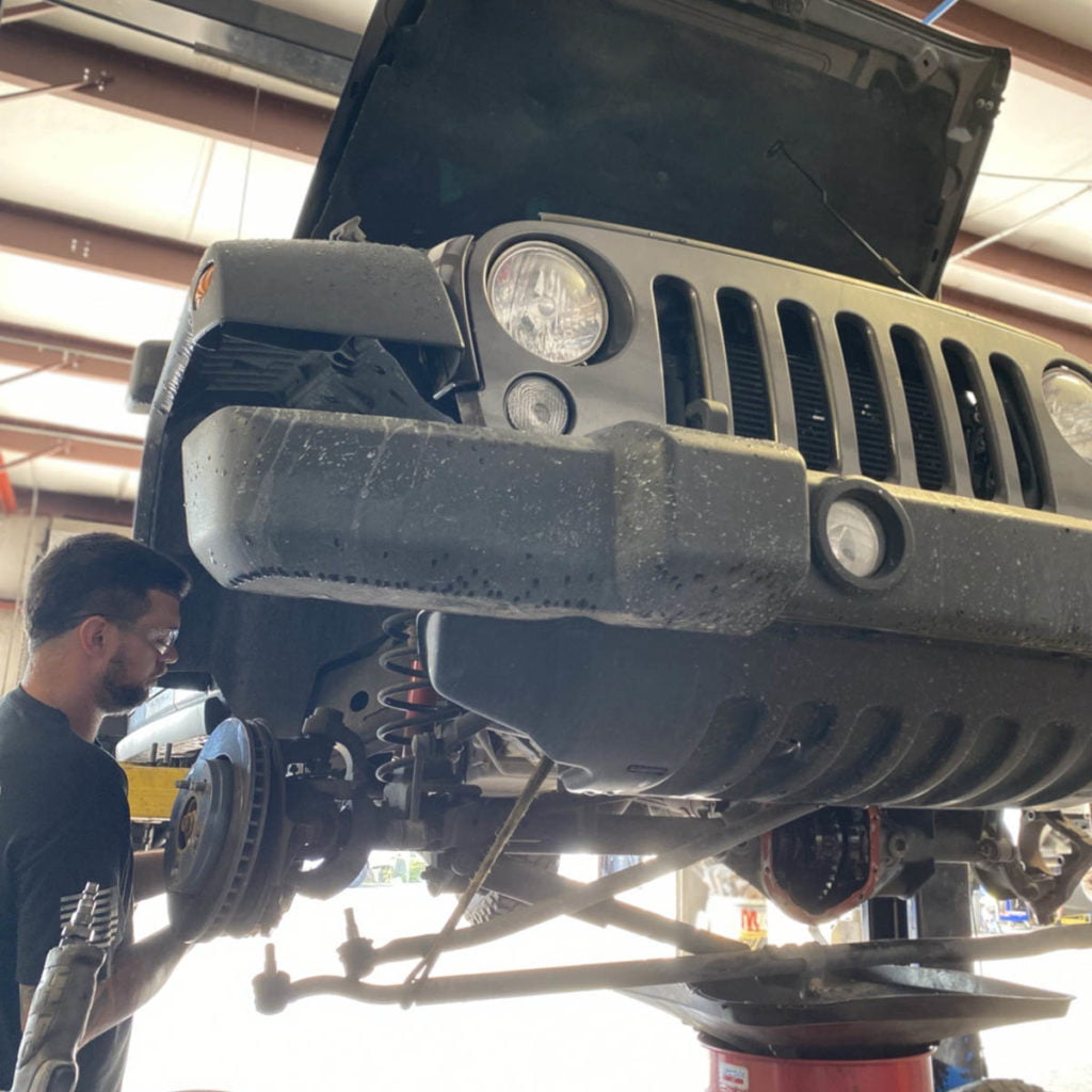 Mechanic at a custom Jeep shop in Stuart working on fixing Jeep death wobble due to control arm bushings problem.